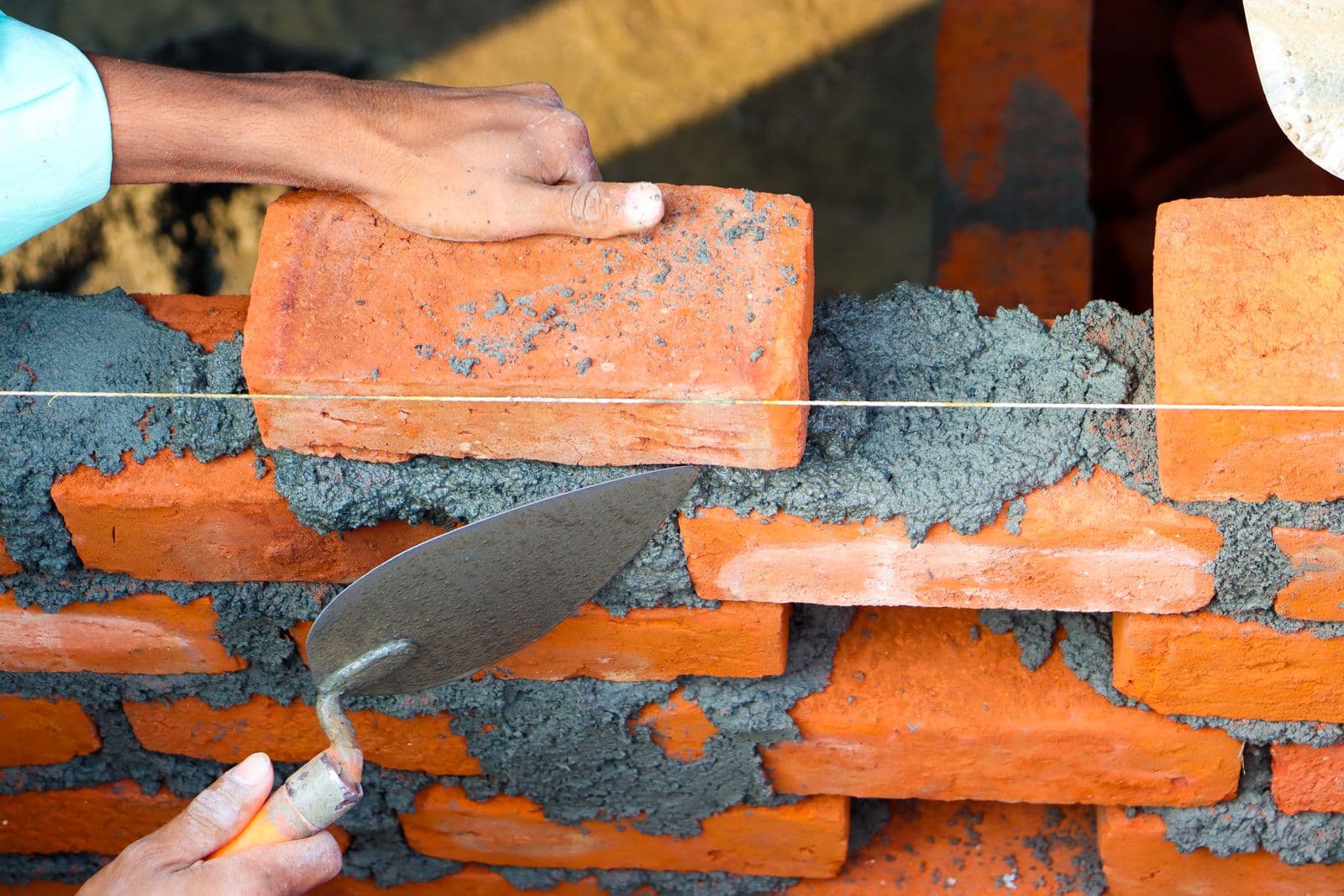 Bricklayer applying cement mortar to a brick wall